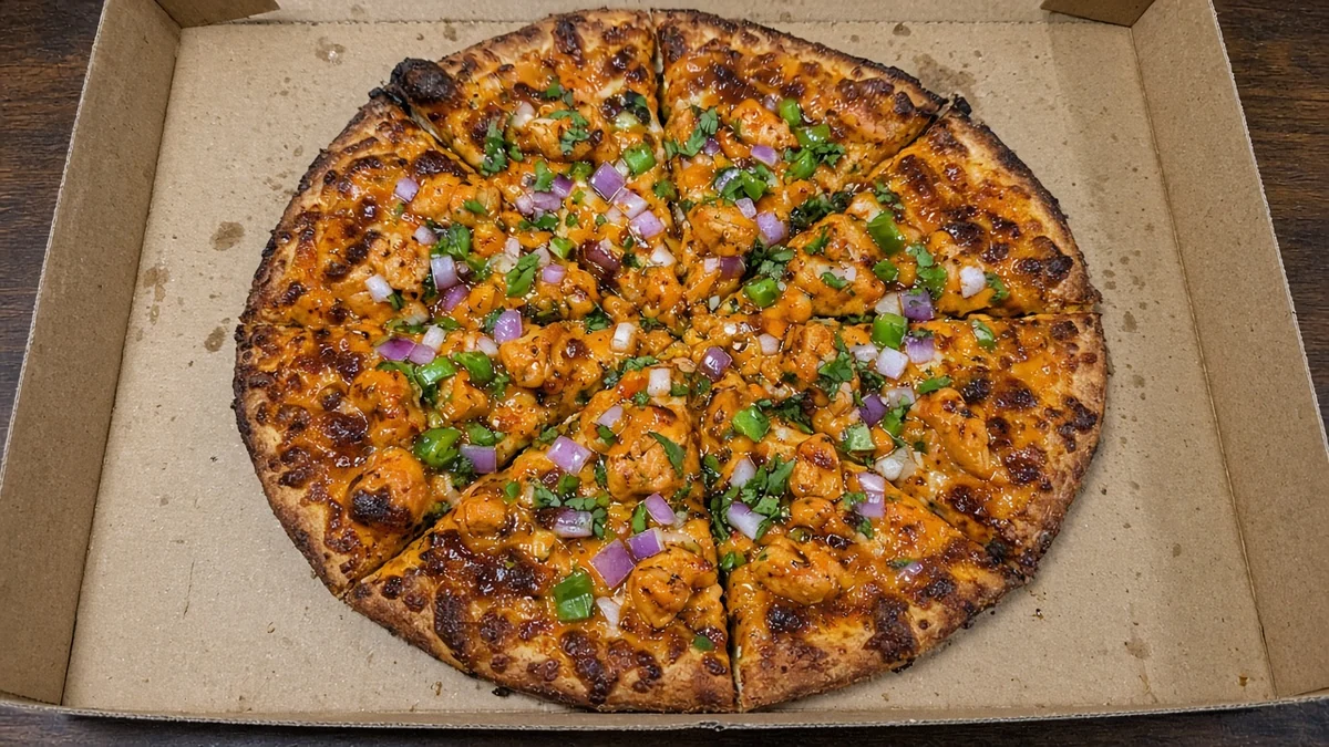 Butter chicken pizza with tandoori chicken, red onion, green peppers and cilantro in an open pizza box